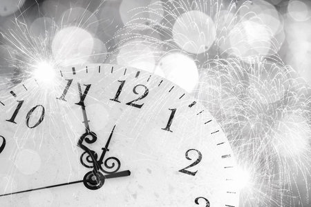 Conceptual image of clock with bokeh lights and firework