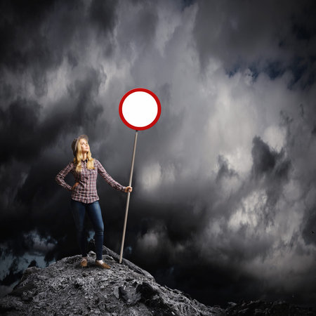 Young woman in casual holding road signの写真素材