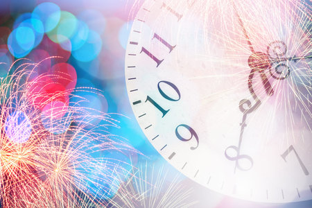 Conceptual image of clock with bokeh lights and firework