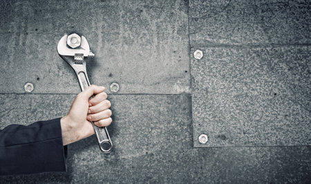 Close up of businessman hand fixing mechanism with spannerの写真素材