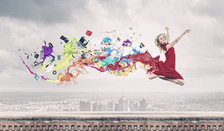 Young woman dancer in red dress jumping highの写真素材