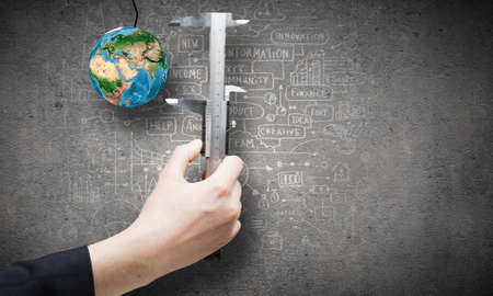 Close up of business person hand measuring Earth planet の写真素材