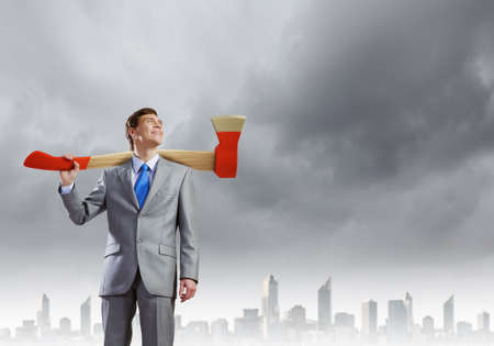 Young businessman holding big axe on shoulderの写真素材