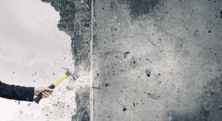 Close up of female hand crashing wall with hammerの写真素材