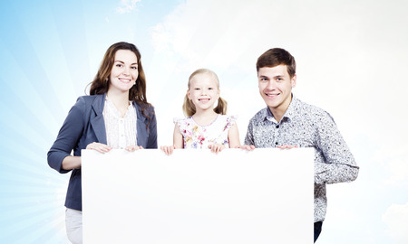 Young happy family with white blank banner  Place for textの写真素材