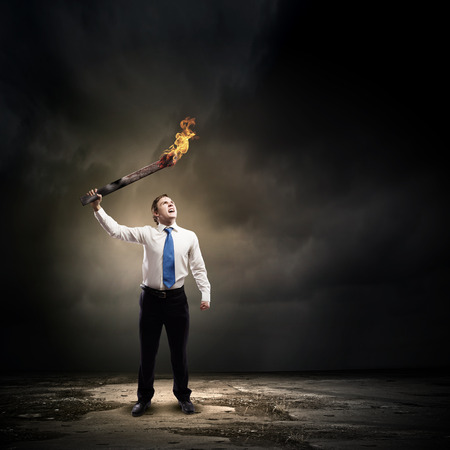 Young businessman holding burning torch in handの写真素材