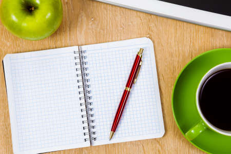 Tablet pc cup of coffee and notepad at tableの写真素材