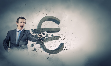 Businessman breaking stone euro symbol with karate punchの写真素材