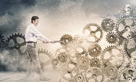 Young businessman fixing gears mechanism with wrenchの写真素材