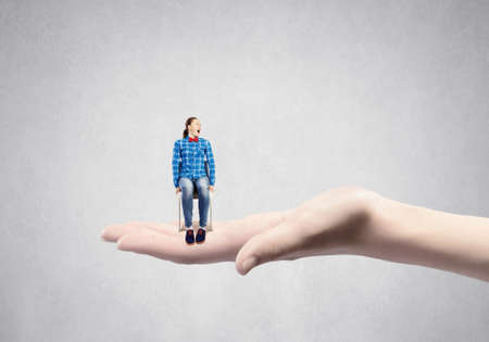 Young woman sitting in chair on female palmの写真素材