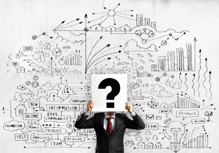 Businessman hiding his face with sheet of paper with sketches at backgroundの写真素材