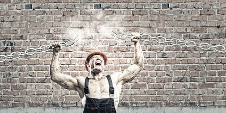 Strong man in uniform tearing metal chain with handsの写真素材