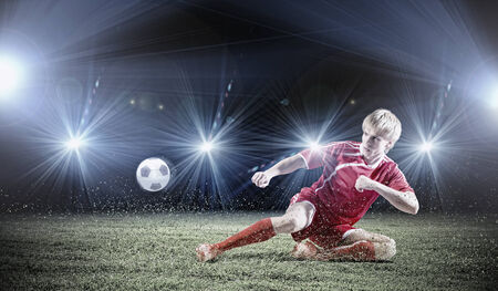 Young football player on stadium kicking ballの写真素材
