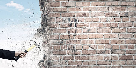 Close up of female hand crashing wall with hammerの写真素材