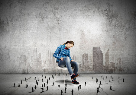 Woman in casual sitting on chair and many small silhouettes of businesspeople aroundの写真素材