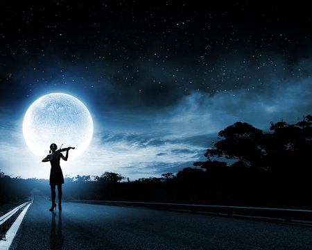 Silhouette of woman playing violin at night