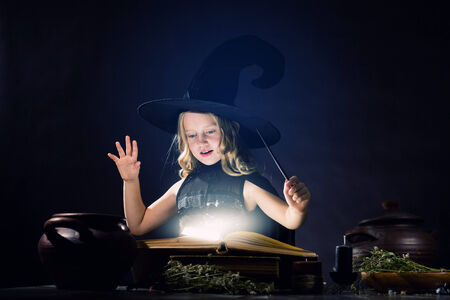 Little Halloween witch reading conjure above potの写真素材