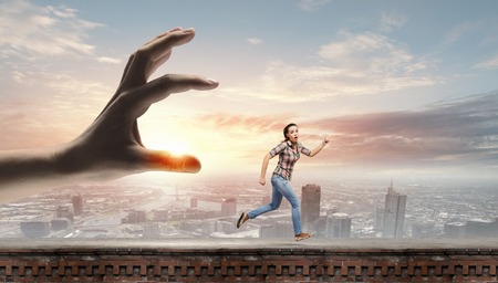 Young woman in casual escaping from big male handの写真素材