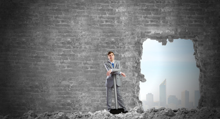 Determined businessman with big hammer in handsの写真素材