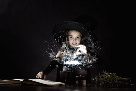 Little Halloween witch reading conjure above potの写真素材