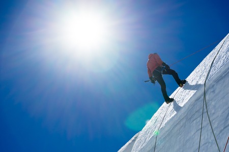 Low angle view of man climbing glacierの写真素材