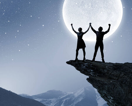 Silhouettes of young couple against full moonの写真素材