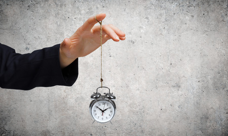 Close up of male hand holding alarm clock on ropeの写真素材
