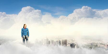 Young girl sitting in chair high in skyの写真素材