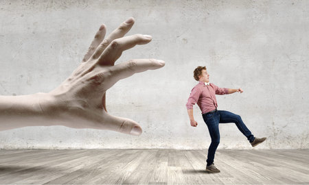 Young man trying to run away from big male hand