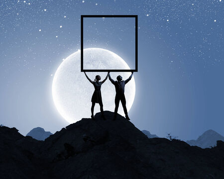 Silhouettes of young couple against full moonの写真素材