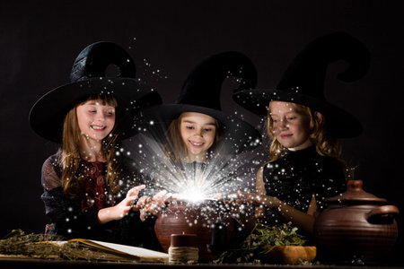 Three little Halloween witches reading spell above pot