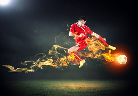 Young football player on stadium in jump taking ballの写真素材