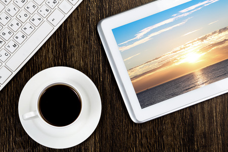 Tablet pc cup of coffee and keyboard at tableの写真素材