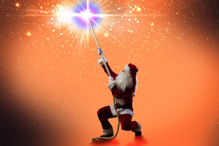 Santa Claus catching star in night sky with ropeの写真素材