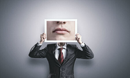 Businessman hiding head behind photo with huge mouthの写真素材