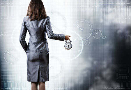 Rear view of businesswoman holding old alarm clockの写真素材