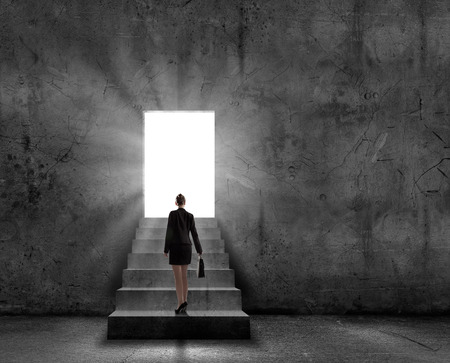Silhouette of businesswoman with briefcase standing in doorwayの写真素材