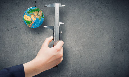 Close up of business person hand measuring Earth planet  Elements of this image are furnished by NASAの写真素材