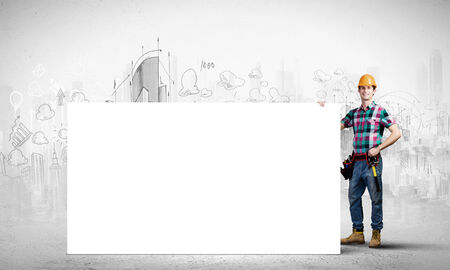 Young repairman holding white blank banner  Place for textの写真素材