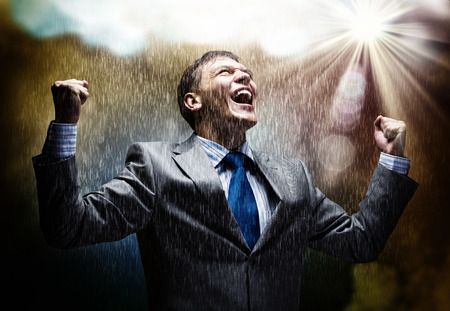 Cheerful businessman with hands up celebrating successの写真素材
