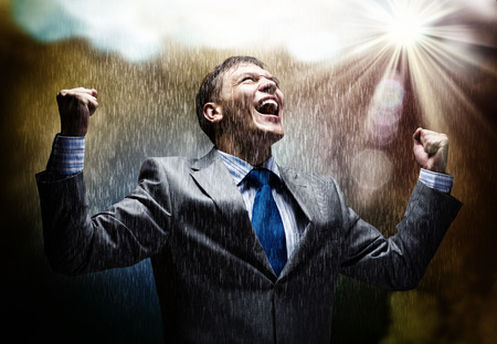 Cheerful businessman with hands up celebrating success