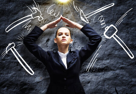 Young troubled businesswoman protecting head with with handsの写真素材