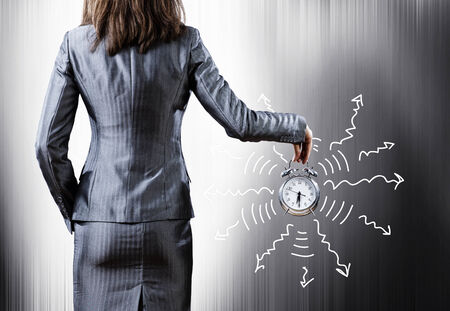 Rear view of businesswoman holding old alarm clockの写真素材