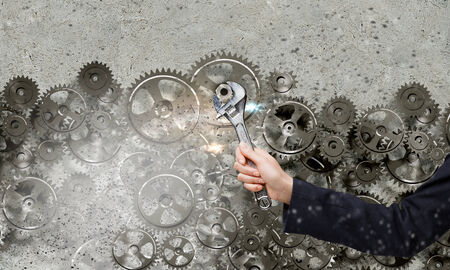 Close up of businessman hand fixing mechanism with spannerの写真素材