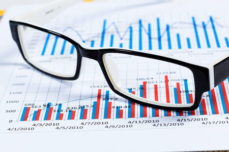 Eye glasses lying on papers with graphs and diagramsの写真素材
