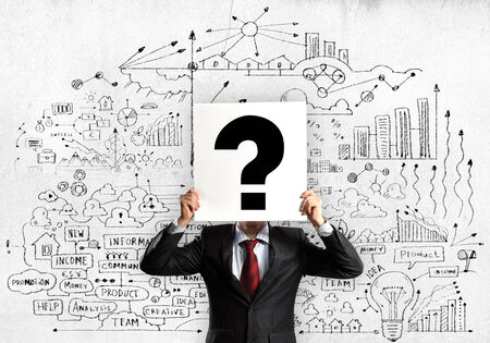 Businessman hiding his face with sheet of paper with sketches at backgroundの写真素材