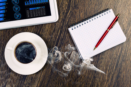 Tablet pc cup of coffee and notepad at tableの写真素材