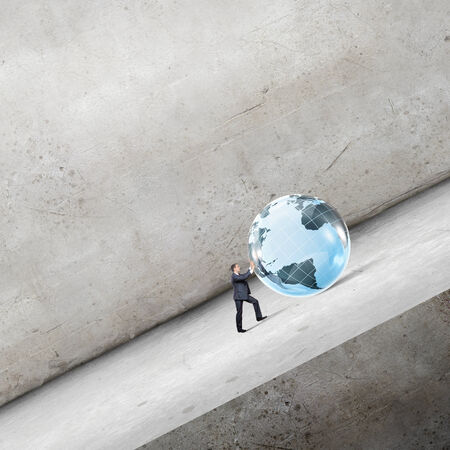 Businessman rolling Earth planet up the hillの写真素材