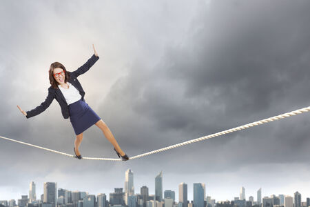 Young attractive businesswoman balancing on rope high in skyの写真素材
