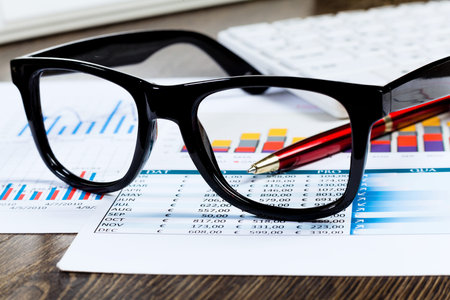 Eye glasses lying on papers with graphs and diagramsの写真素材